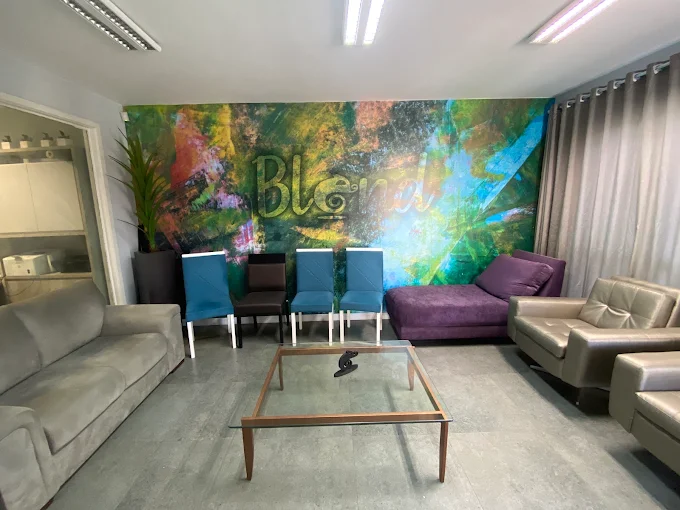 Recepção da Blend com sofás, cadeiras azuis e um painel colorido com o nome Blend na parede